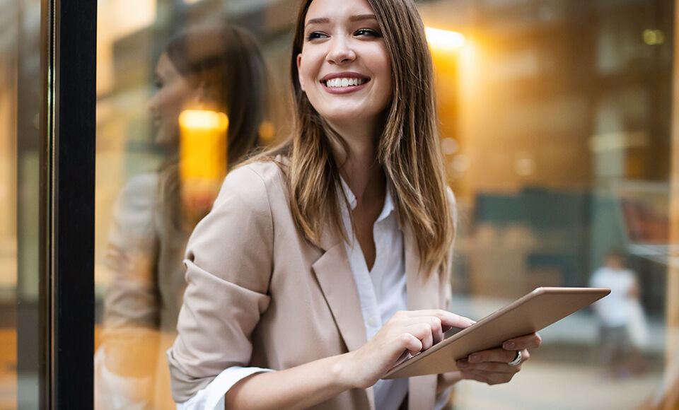jeune femme sur sa tablette souriant dans la rue