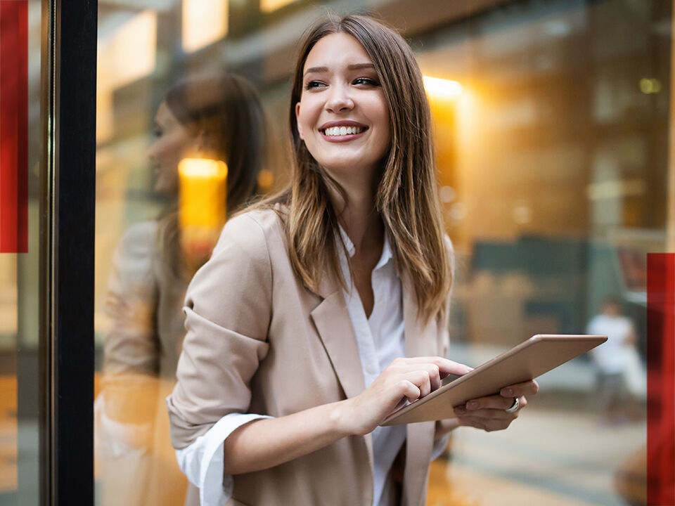 jeune femme sur sa tablette souriant dans la rue