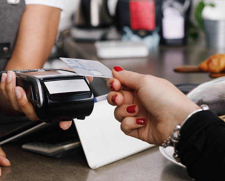 Une main dépose sa carte bancaire sur un TPE.