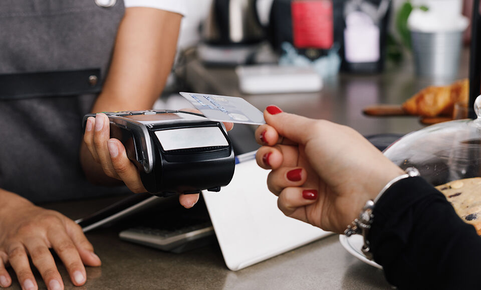 Une main dépose sa carte bancaire sur un TPE.