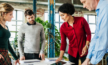 Groupe de personnes travaillant ensemble sur un sujet en entreprise.