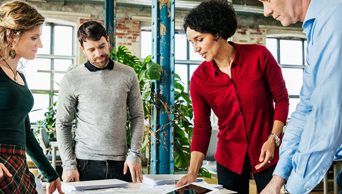 Groupe de personnes travaillant ensemble sur un sujet en entreprise.