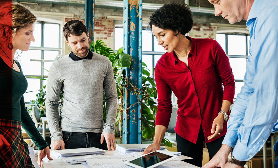 Groupe de personnes travaillant ensemble sur un sujet en entreprise.