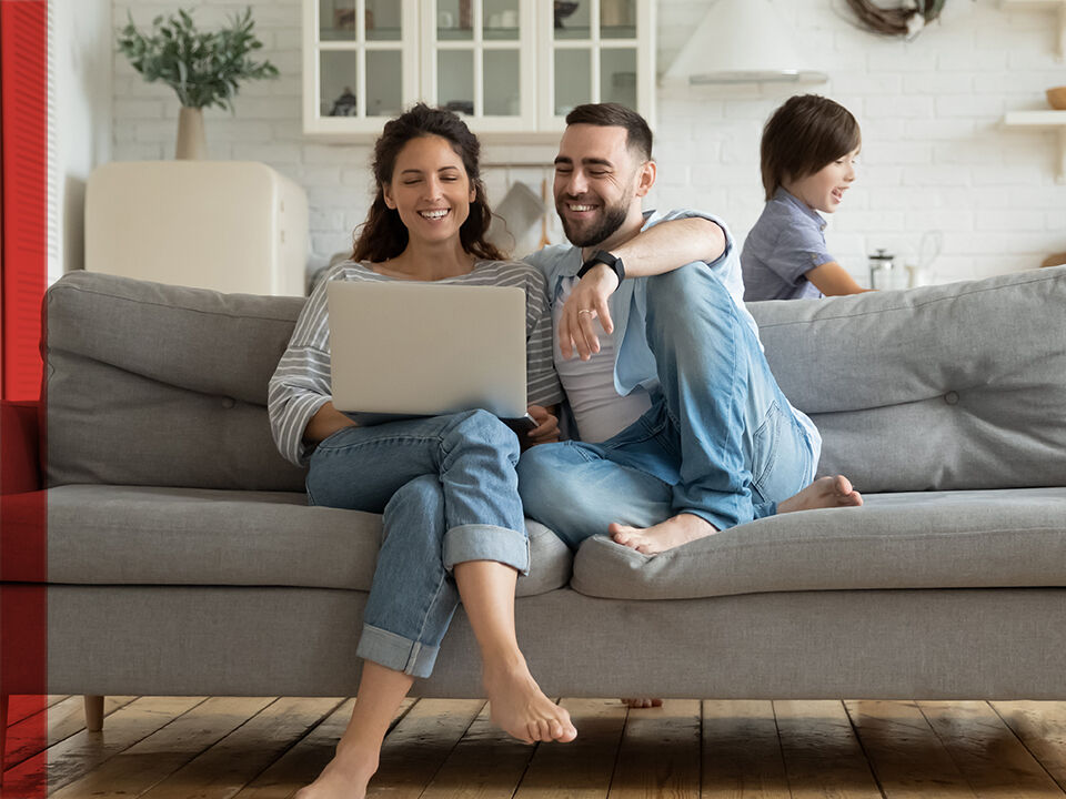 Couple avec enfant sur un canap&eacute; devant un ordinateur