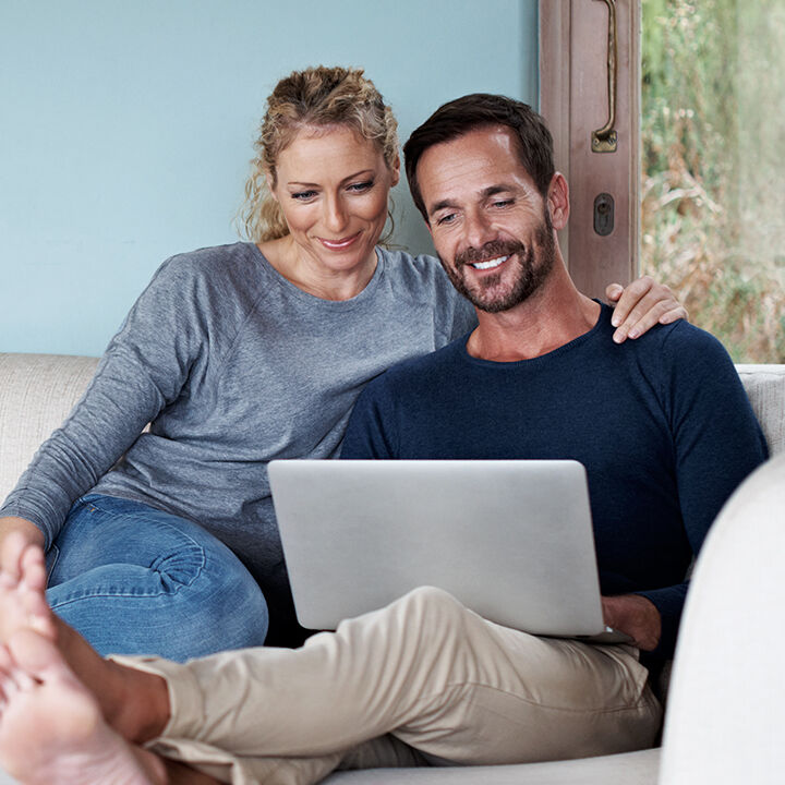 Une femme et un homme assis dans un canap&eacute; avec un ordinateur