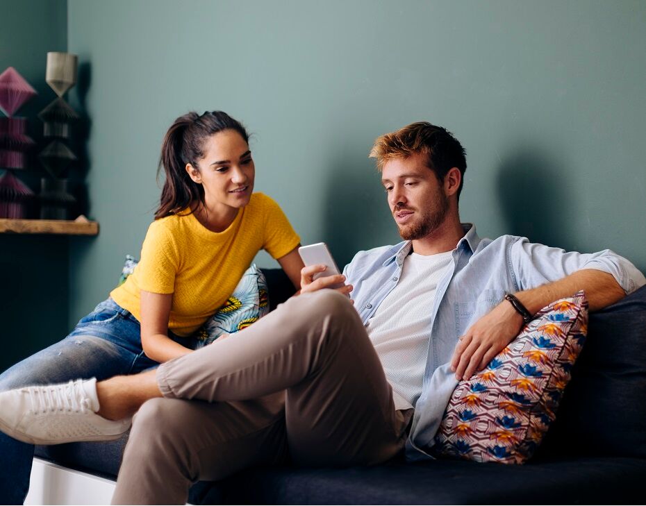 Couple homme et femme sur canap&eacute; avec smartphone