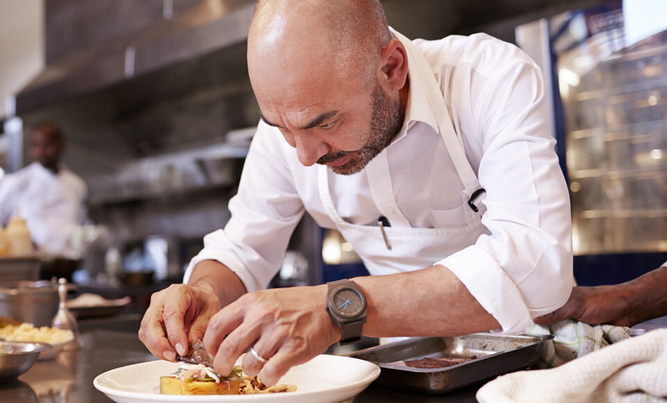 Homme qui pr&eacute;pare un plat dans la cuisine d'un restaurant