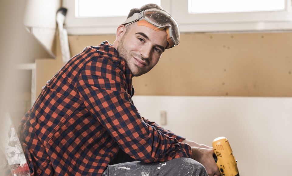 Homme assis qui tient une perceuse