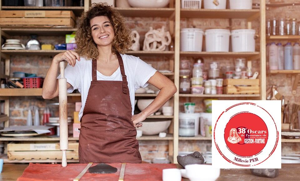 Une femme dans son atelier regarde devant elle.